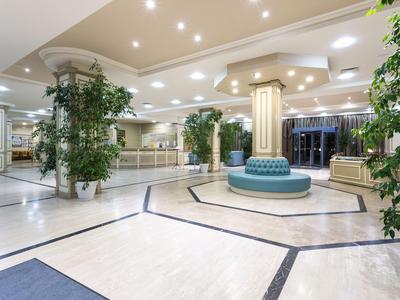 Helle und geräumige Hotellobby mit Polstersitz, Säulen und großen Pflanzen.