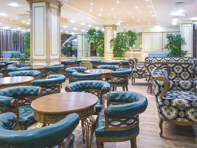 Elegant hotel lounge with blue armchairs and round wooden tables in bright, stylish setting