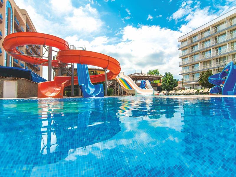 Water park with various slides next to a hotel under blue sky