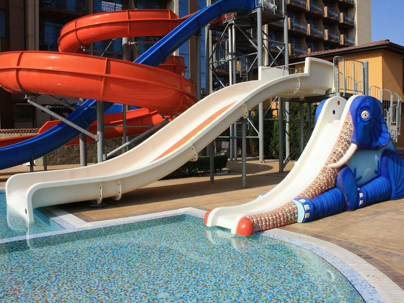 Two water slides by the pool, one white and one blue, with a blue elephant figure at the edge.