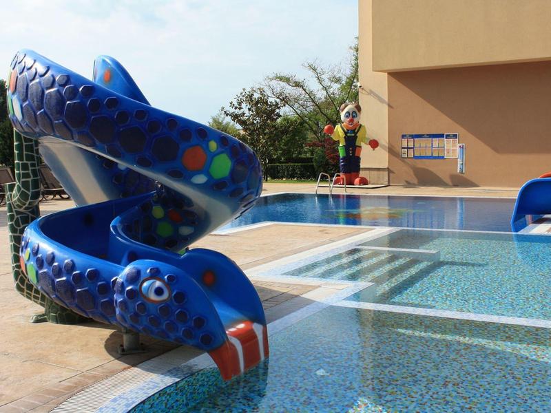 Blue snake-shaped water slide at a hotel pool on a sunny day.