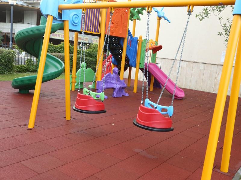 Colorful children's playground with swings, slide, and climbing frame on soft flooring
