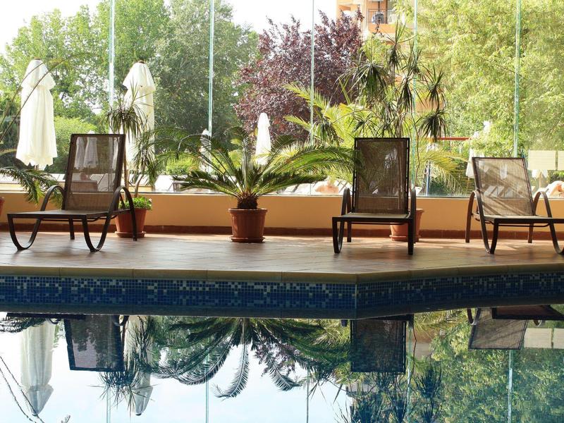 Inviting swimming pool with lounge chairs and plants on a terrace overlooking greenery.