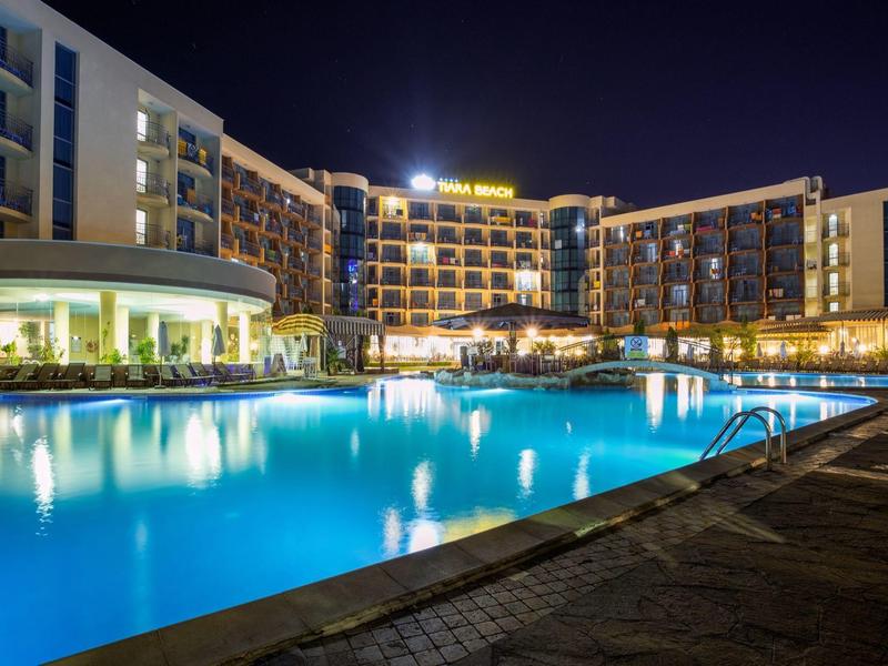 Modern hotel with illuminated pool at night under clear sky.