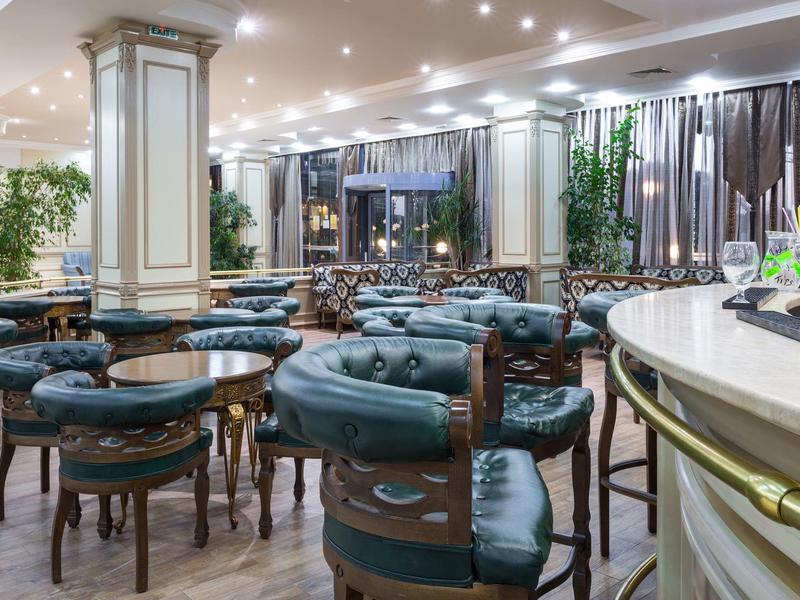 Elegant hotel bar area with leather chairs, wooden tables, and ambient lighting.