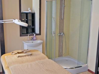 Gezellige spakamer met massagetafel, spiegel en moderne douche in zacht licht.