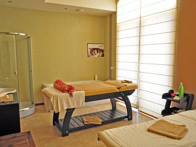 Gezellige massageruimte met twee tafels, zacht licht en een groot raam met jaloezieën.