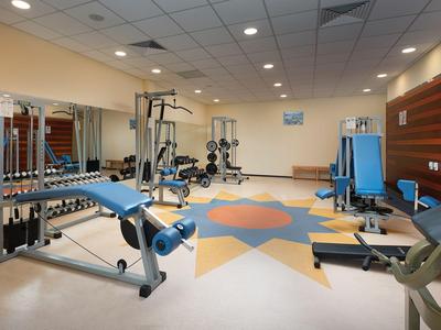 Moderner Fitnessraum mit verschiedenen Trainingsgeräten und Farbgestaltung am Boden.