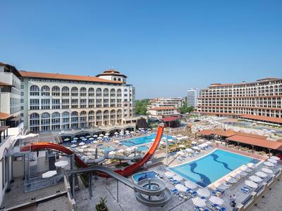 Großes Hotel mit mehreren Pools, Wasserrutschen und vielen Liegestühlen unter klarem Himmel.