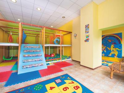 Kinderspielbereich mit Klettergerüst, bunten Matten und Spielzeug in hellem Raum.