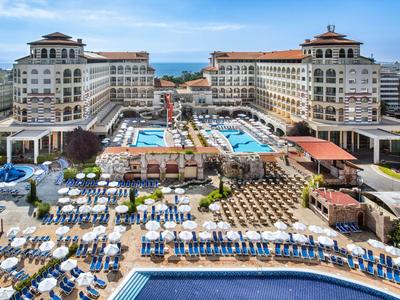 Luxuriöses Hotel mit mehreren Pools, Liegestühlen und Blick auf das Meer.