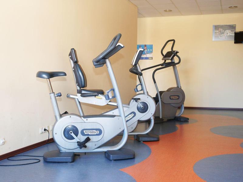 Rij vaste fitnessfietsen in een kleine, helder verlichte binnenfitnessruimte.