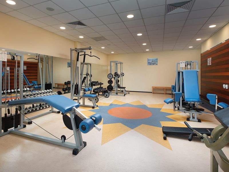 Ruime hotelgym met diverse fitnessapparaten en kleurrijk vloermotief.