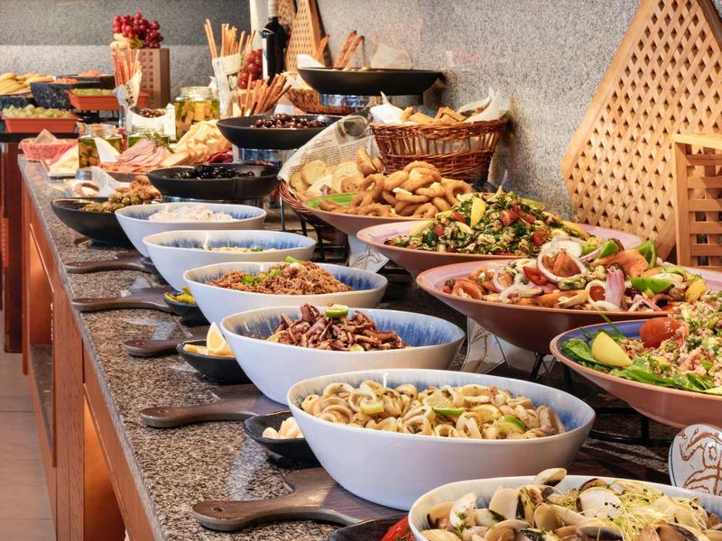 Een lange buffettafel gevuld met verschillende salades en gerechten in kommen en manden.