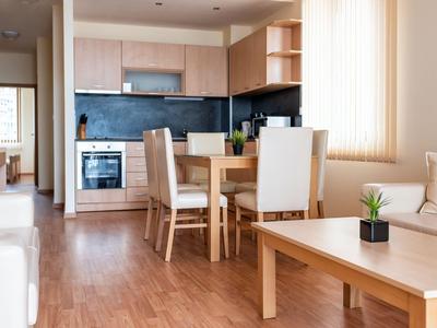 Helle Küchen- und Essbereich in einer modernen Ferienwohnung mit Holzboden und weißer Einrichtung.