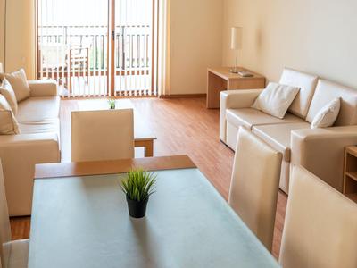 Modern eingerichtetes Wohnzimmer mit Sofa, Sesseln und Balkon in einem Hotelappartement.