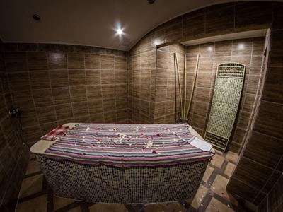 Dimly lit small spa room with massage table and tiled walls