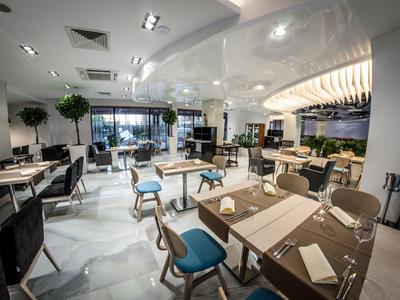 Modern restaurant with stylish tables, blue chairs, and large windows providing plenty of daylight.