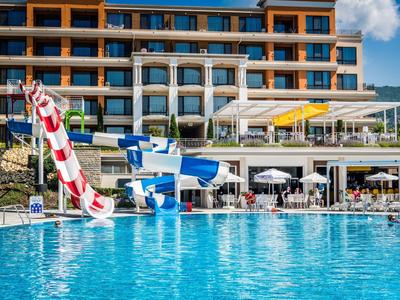 Ein Pool mit Wasserrutschen vor einem modernen Hotelgebäude bei sonnigem Wetter.