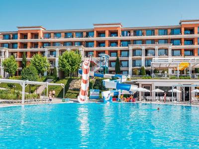 Hotel mit großem Außenpool, Wasserrutschen und Liegestühlen im sonnigen Wetter.