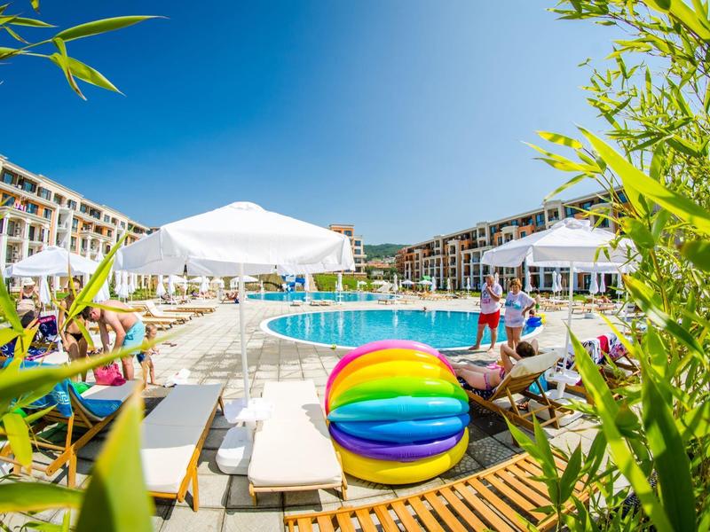 Colorful ball by pool with lounge chairs and umbrellas at a hotel resort