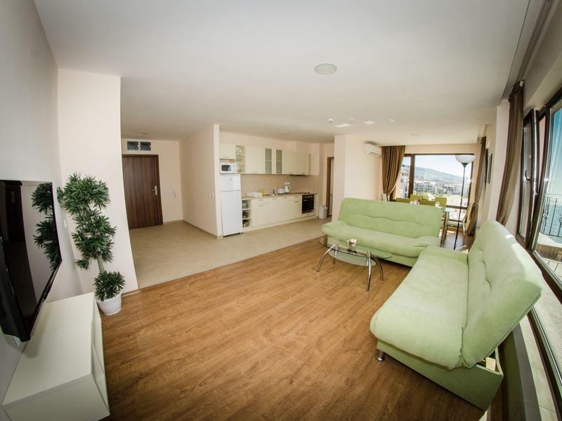 Bright living room with wooden floor, two sofas, and large window overlooking the harbor.
