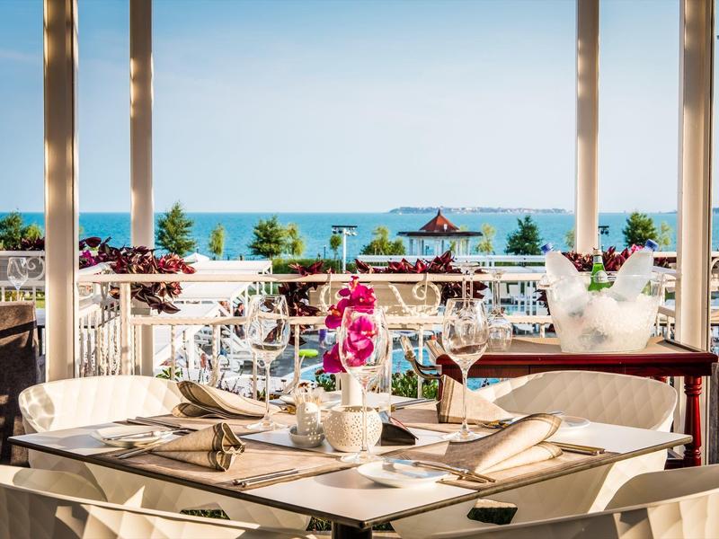 Open restaurant with decorated tables and sea view under clear sky