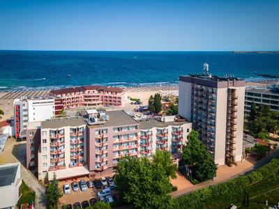 Mehrere mehrstöckige Hotels und Gebäude an einem sonnigen Strand mit blauem Himmel und Meer im Hintergrund.