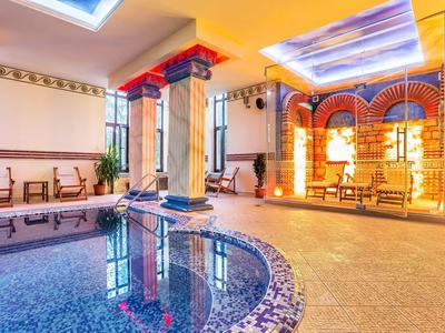 Indoor pool area with elegant columns, warm lighting, and comfortable seating in a hotel.