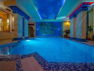 Beheiztes Hallenbad mit blauer Beleuchtung und dekorativer Decke in luxuriösem Ambiente.