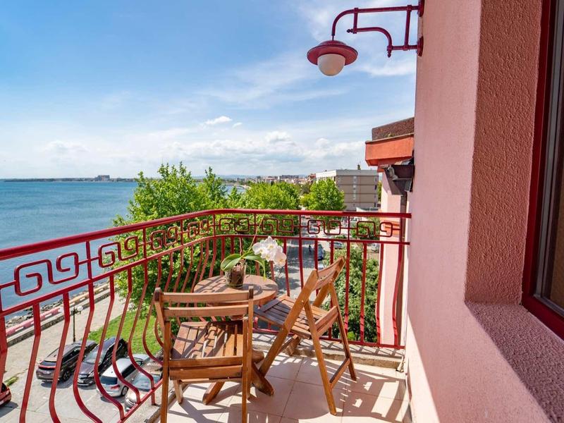 Balcony with wooden furniture and sea view under clear sky