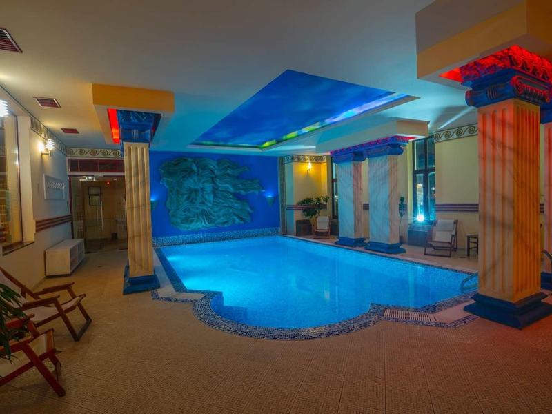 Indoor pool with blue lit ceiling and color-accented pillars in a hotel