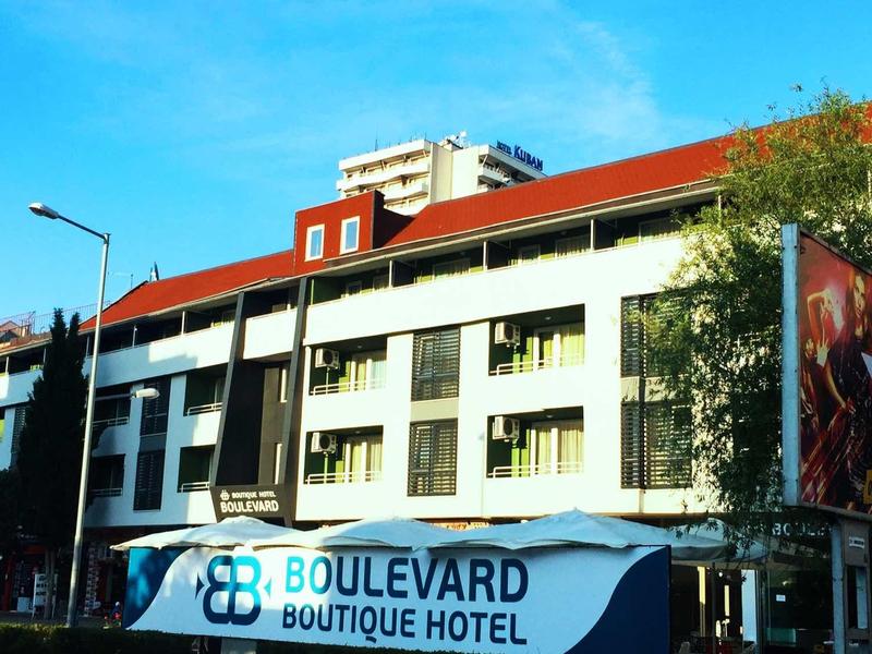 Modern Boulevard Boutique Hotel met witte gevel en rood dak op een zonnige dag