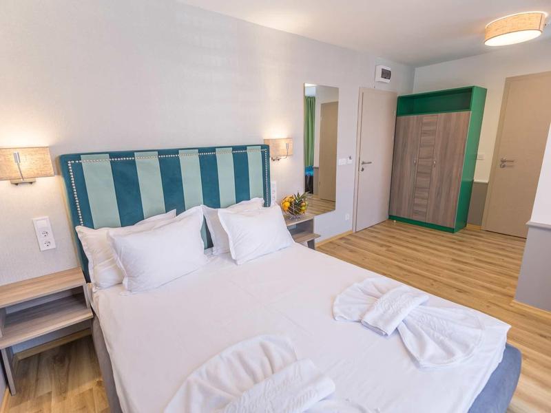 Modern hotelkamer met tweepersoonsbed, nachtkastjes en grote kledingkast.