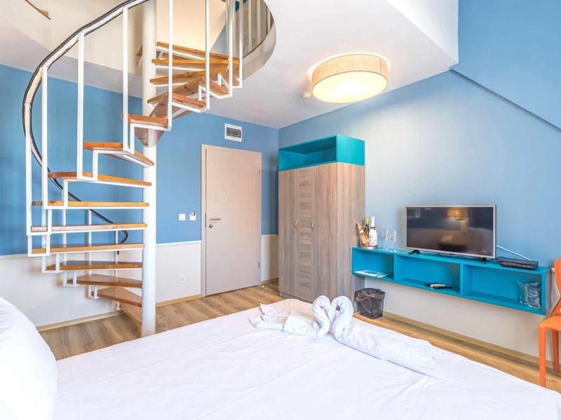 Lichte hotelkamer met wenteltrap, blauwe muren en modern meubilair.