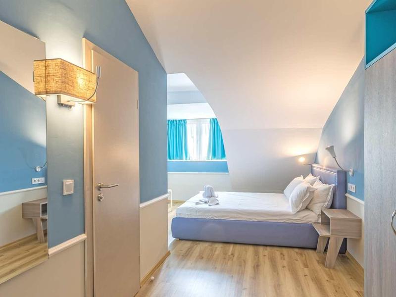 Lichte, moderne hotelkamer met twee bedden, houten vloer en indirecte verlichting.