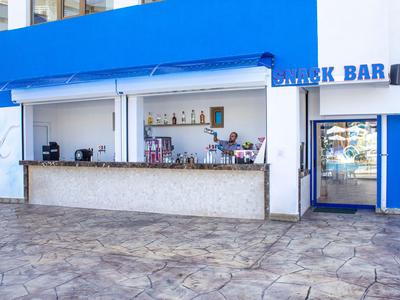 Open beach bar with blue awning and counter in front of a light blue building