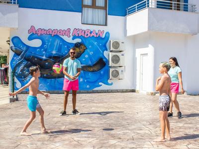Four people playing outside in front of a building with a blue sea turtle mural.