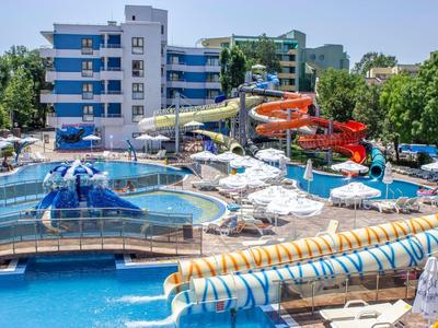 Wasserpark mit mehreren Wasserrutschen, Pools, Sonnenschirmen und Liegestühlen an einem sonnigen Tag.