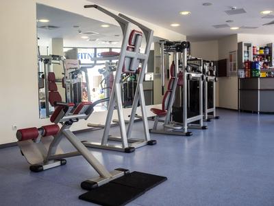 Modern gym with various exercise machines and blue flooring.