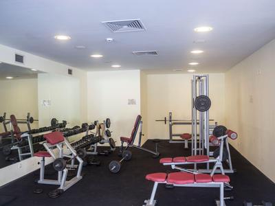 Small gym room with various exercise equipment and a mirror on the wall.