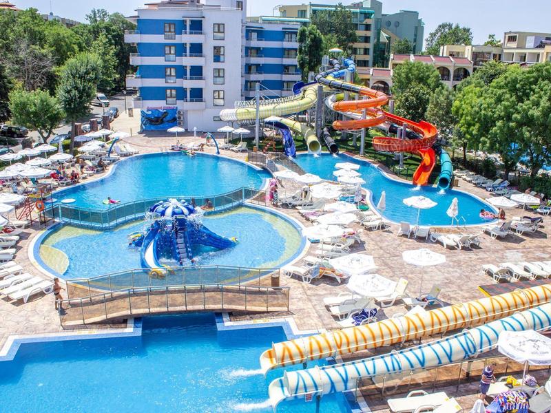 Outdoor pool with water slides and lounge chairs at a sunny vacation spot.