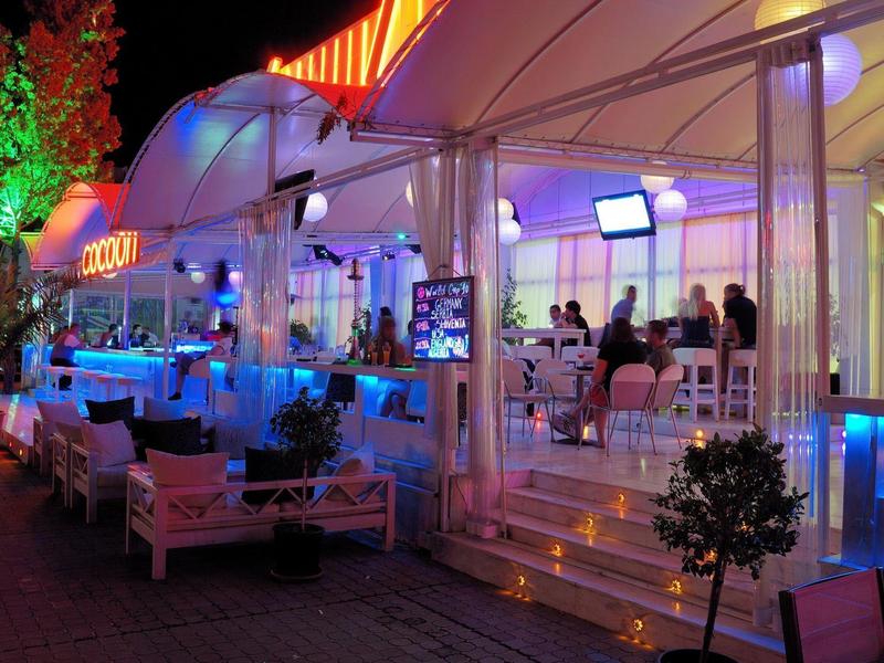 Brightly lit hotel buffet area with food on both sides and tables in the background.