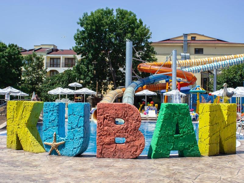 Large colorful letters 'KUBAN' in front of a water park with slides and umbrellas