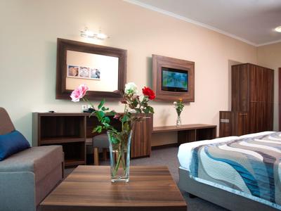 Modern ingerichte hotelkamer met bed, bank, kast en een boeket bloemen op de tafel.