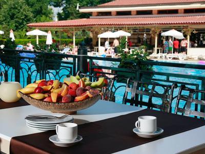 Tafel met fruitmand en koffiekopjes naast een hotelzwembad buiten.