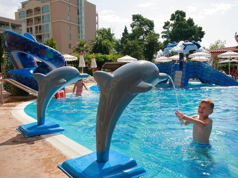 Kinderen spelen in een zwembad met dolfijn waterattracties bij een hotelresort.