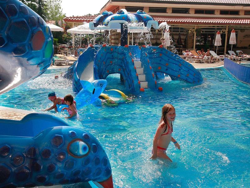 Kinderen spelen in een kleurrijke waterspeeltuin met dolfijnglijbanen en zwembaden.