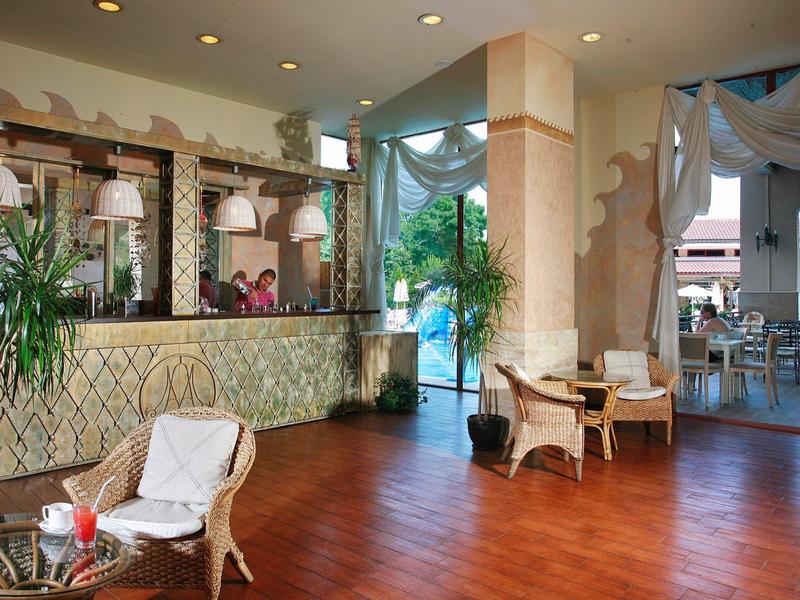 Elegante hotelhal met receptiebalie, stoelen en planten in een lichte omgeving.