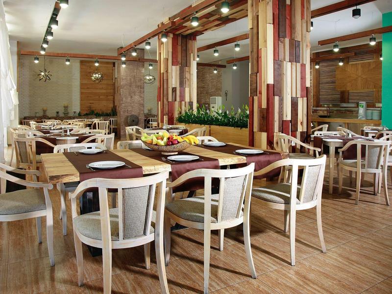 Modern restaurant met houten meubels, kleurrijke muren en veel tafels en stoelen.